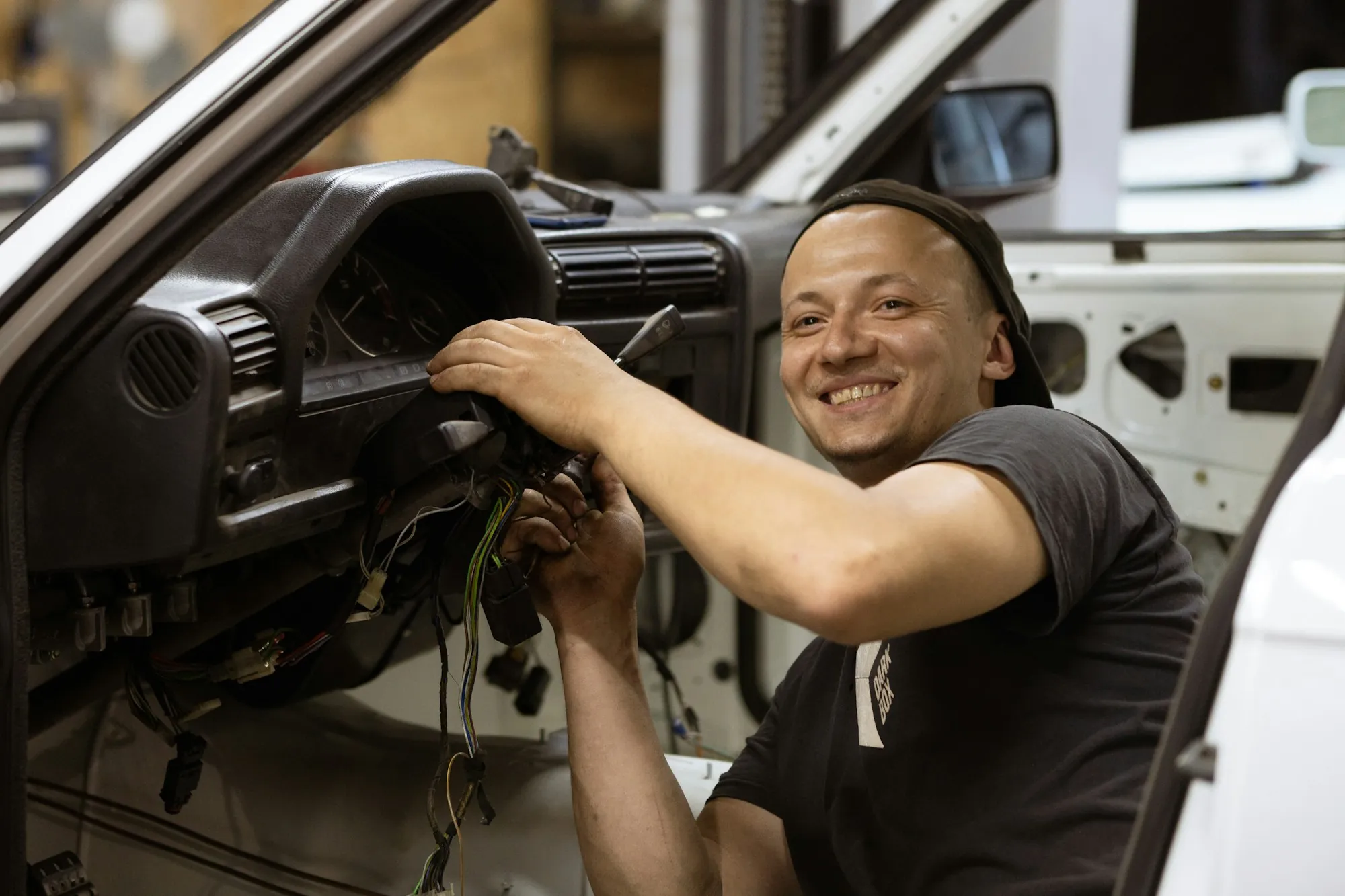 Smiling technician working inside a vehicle cabin
