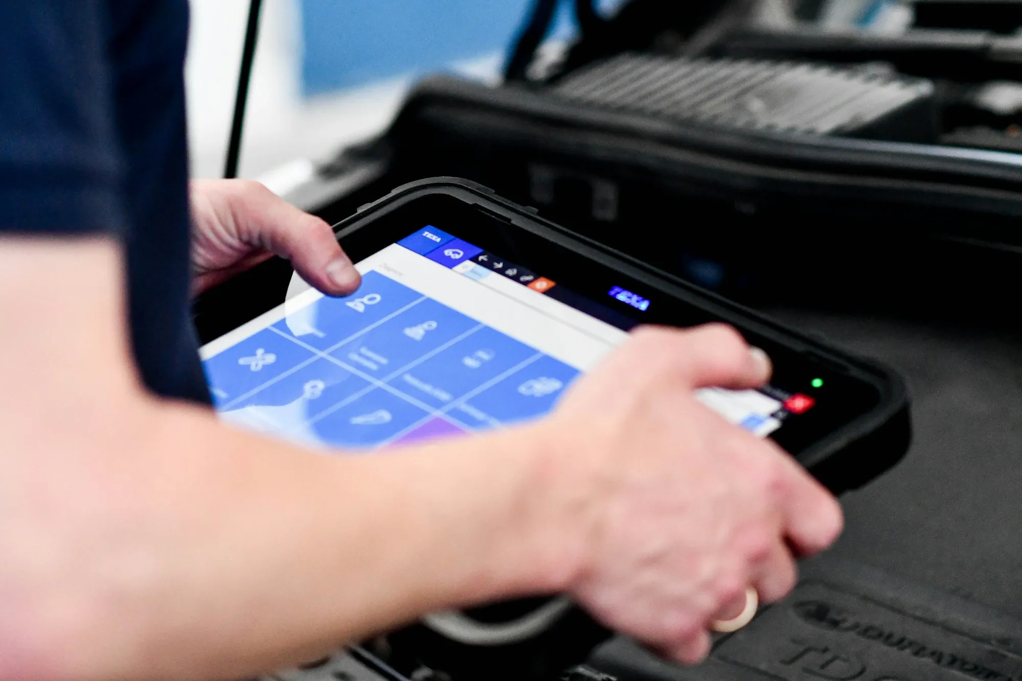 Hand holding a diagnostic tablet with vehicle data on screen