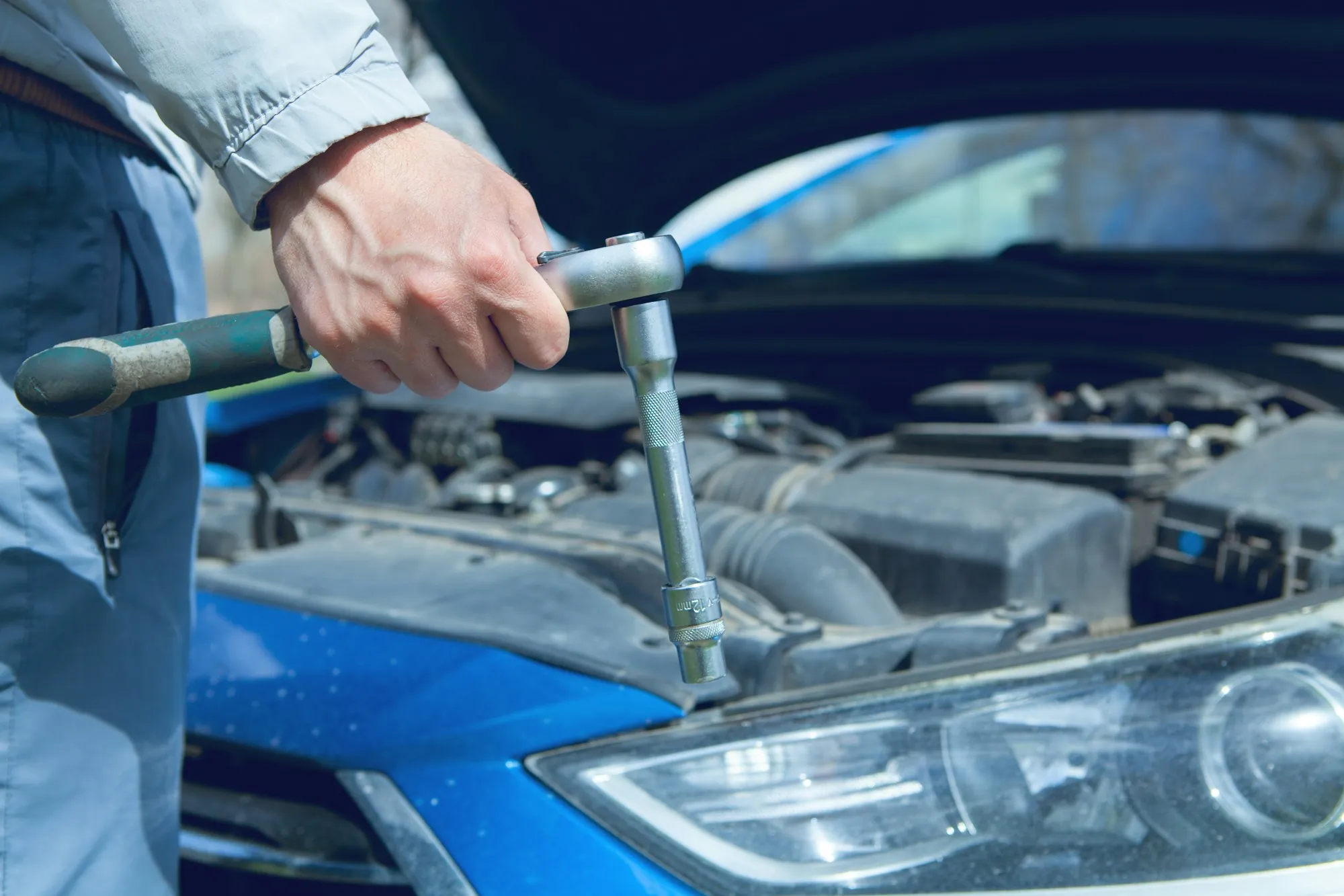 Mechanic working on an engine with tools in hand