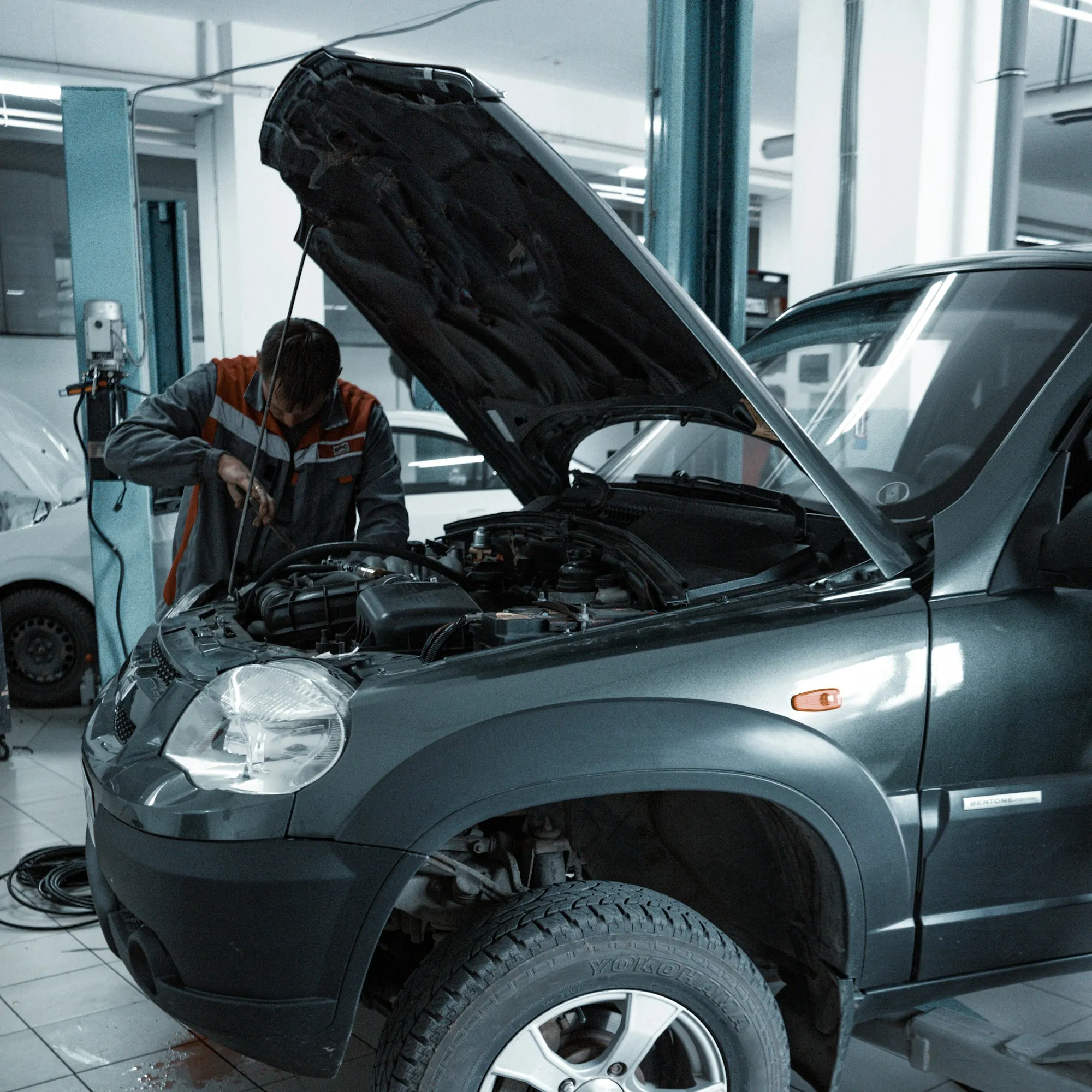Car with its hood open on a lift inside a repair shop